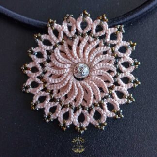 Collier „Clio“ aus handgefertigter Frivolitätenspitze in Zartrosa/Lachs mit rundem Anhänger, silber galvanisierter Lavaperle in der Mitte und bronzefarbigen Rocailles. Die schwarze Textilhalskette hat einen silberfarbenen Verschluss mit Verlängerungskette.