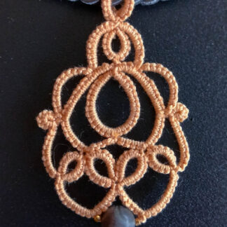 Collier „Loreen“ aus handgefertigter Frivolitätenspitze in Pfirsichfarbe mit grauer Halbedelsteinperle und goldfarbigen Rocailles. Kombiniert mit einer grauen Kordel mit goldfarbenem Magnet-/Bajonette-Verschluss.