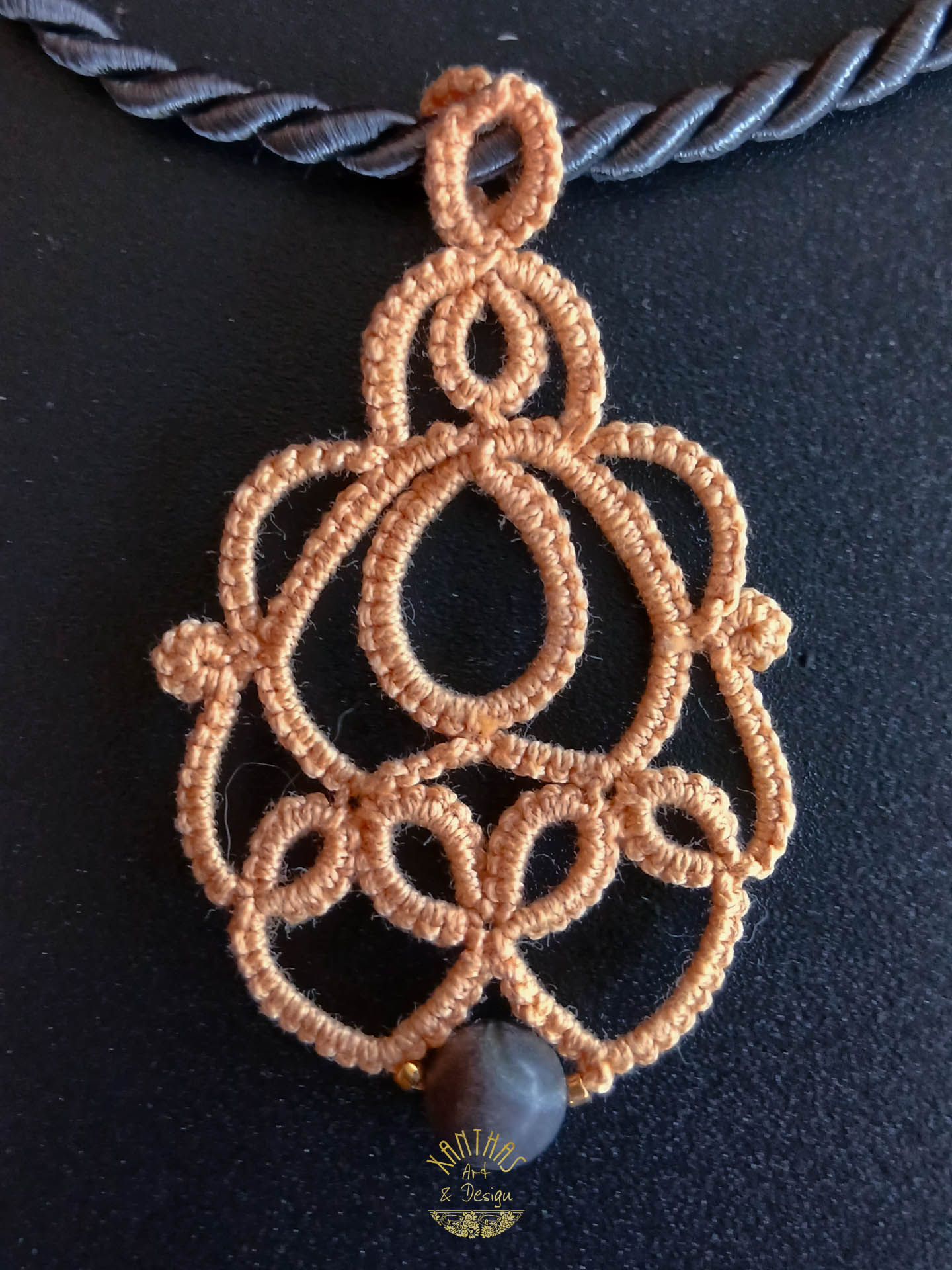 Collier „Loreen“ aus handgefertigter Frivolitätenspitze in Pfirsichfarbe mit grauer Halbedelsteinperle und goldfarbigen Rocailles. Kombiniert mit einer grauen Kordel mit goldfarbenem Magnet-/Bajonette-Verschluss.