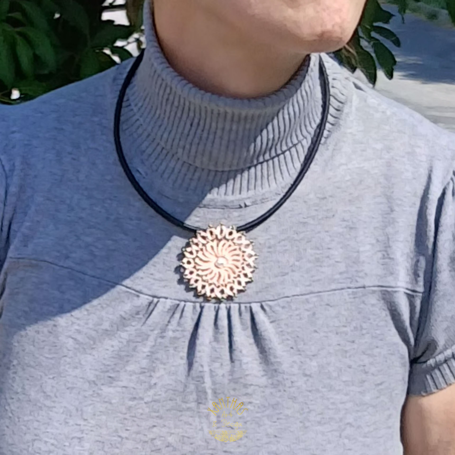 Collier „Clio“ aus handgefertigter Frivolitätenspitze in Zartrosa/Lachs mit rundem Anhänger, silber galvanisierter Lavaperle in der Mitte und bronzefarbigen Rocailles. Die schwarze Textilhalskette hat einen silberfarbenen Verschluss mit Verlängerungskette.