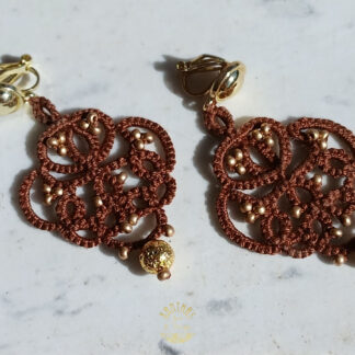 Ohrclips „Amandine“ aus handgefertigter Frivolitätenspitze in Dunkelbraun mit gold bedampften Rocailles und gold galvanisierten Lavaperlen. Die Ohrclipspatente sind aus goldfarbigem Metall.