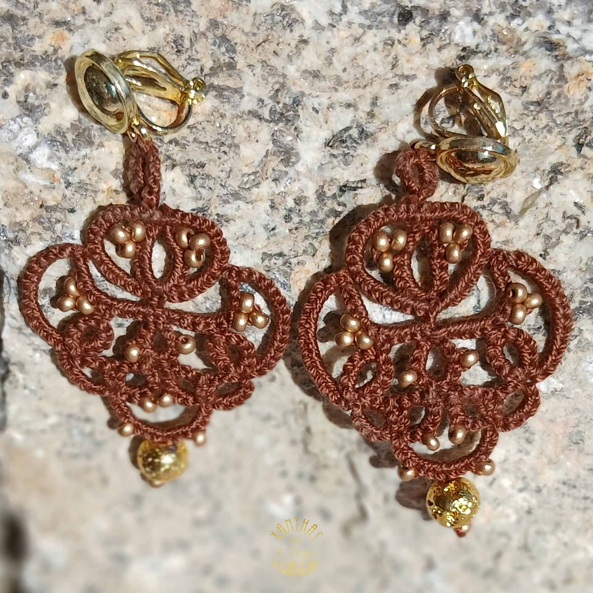 Ohrclips „Amandine“ aus handgefertigter Frivolitätenspitze in Dunkelbraun mit gold bedampften Rocailles und gold galvanisierten Lavaperlen. Die Ohrclipspatente sind aus goldfarbigem Metall.