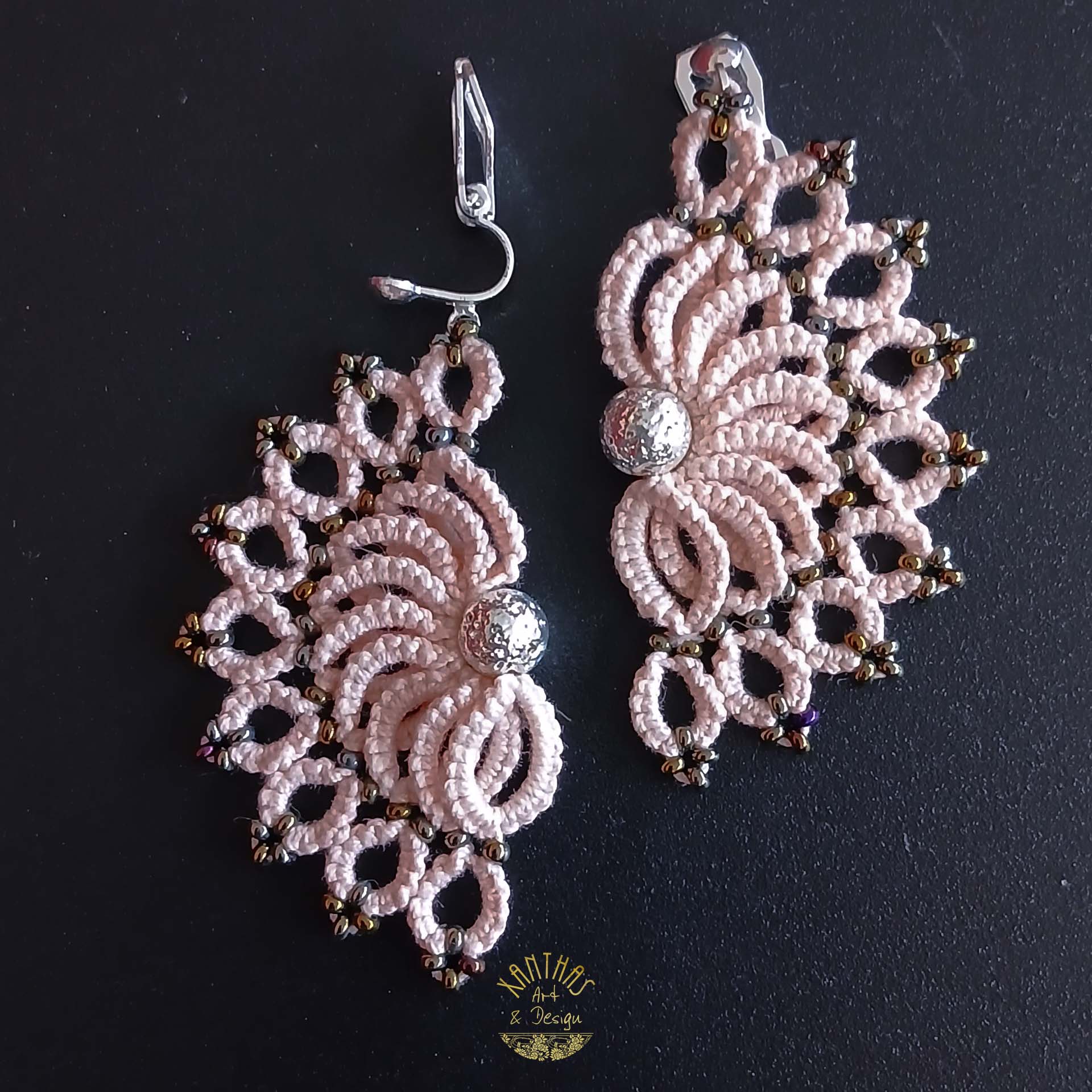 Ohrclips „Clio“ aus handgefertigter Frivolitätenspitze in Zartrosa/Lachs mit halbmondförmigem Design, silber galvanisierter Lavaperle in der Mitte und bronzefarbigen Rocailles. Die Ohrclips sind aus 925 Sterling Silber.