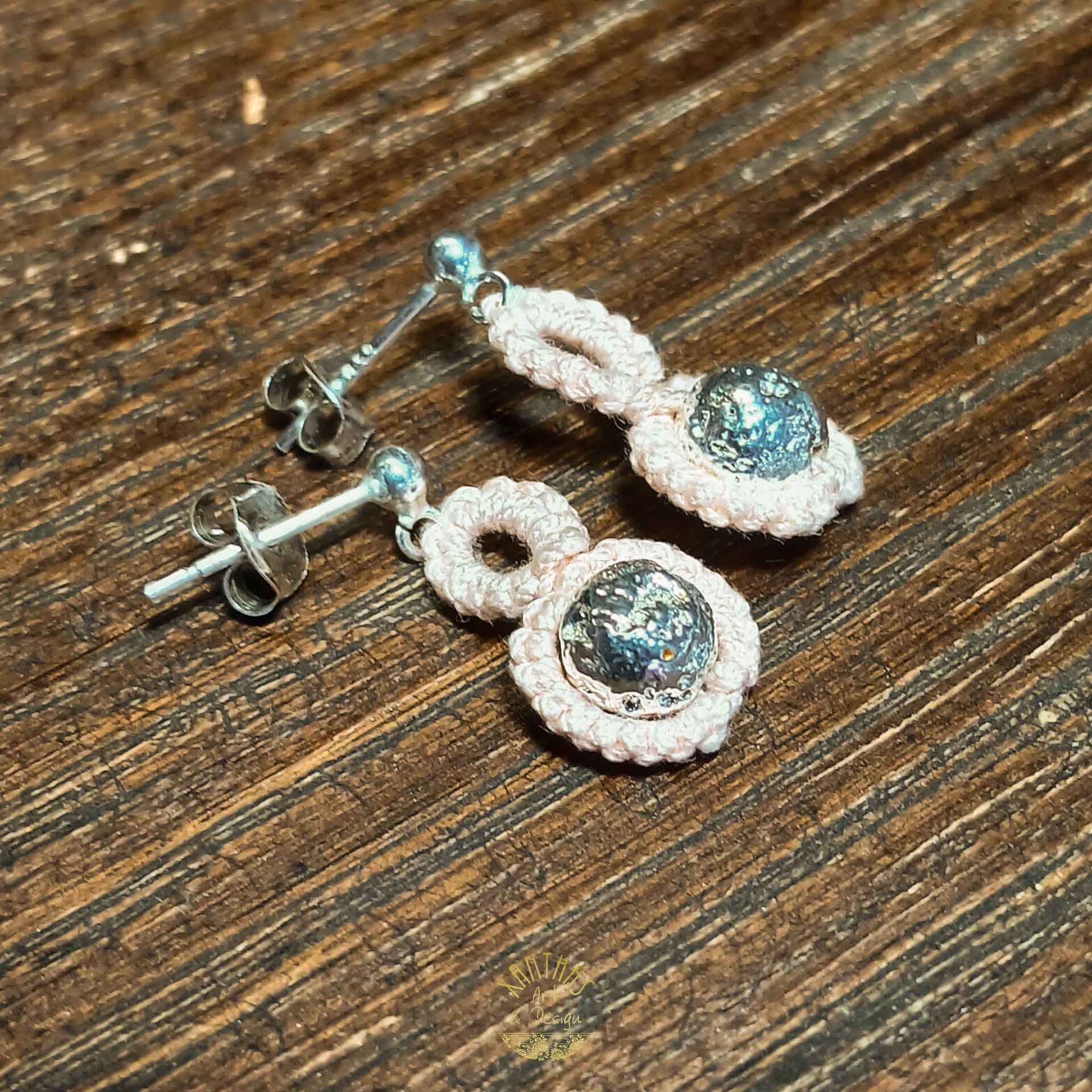 Handgefertigte Ohrstecker „Adriana“ aus zartrosa/lachsfarbigem Baumwollgarn in Frivolitätenarbeit (Schiffchenspitze). Hauptmerkmal ist die silber galvanisierte Lavaperle, die mit Schiffchenspitze umarbeitet ist. Die Ohrstecker sind aus 925 Sterling Silber.