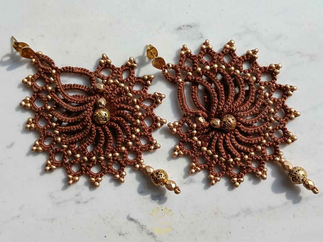 Handgefertigte Ohrringe in dunkelbraun mit goldenen Perlen und Edelstahl-Ohrsteckern. Geknüpft aus Baumwollgarn und mit goldenen Akzenten verziert.