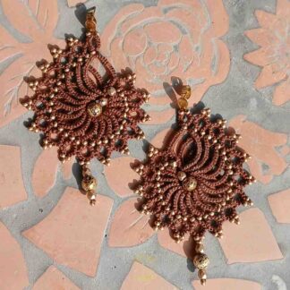 Handgefertigte Ohrringe in dunkelbraun mit goldenen Perlen und Edelstahl-Ohrsteckern. Geknüpft aus Baumwollgarn und mit goldenen Akzenten verziert.