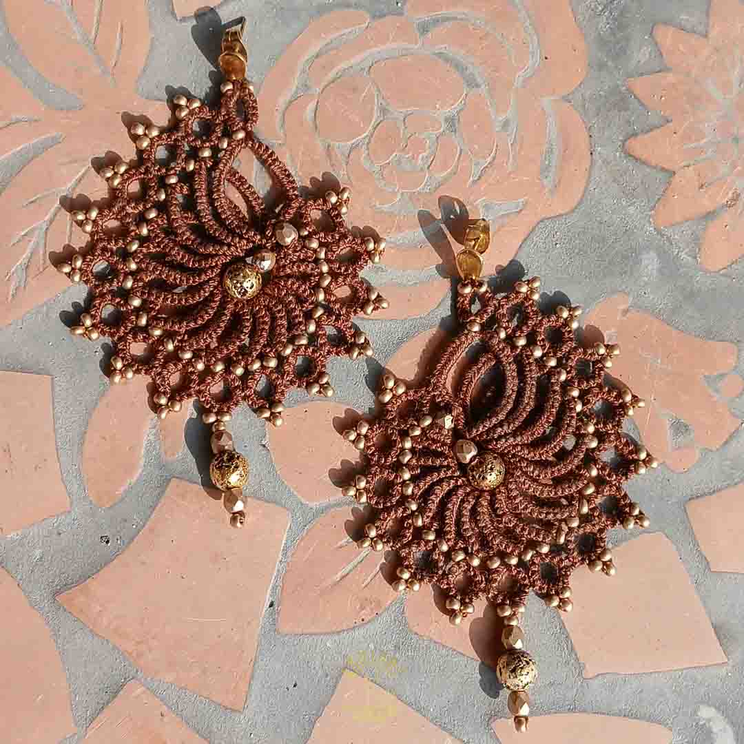 Handgefertigte Ohrringe in dunkelbraun mit goldenen Perlen und Edelstahl-Ohrsteckern. Geknüpft aus Baumwollgarn und mit goldenen Akzenten verziert.